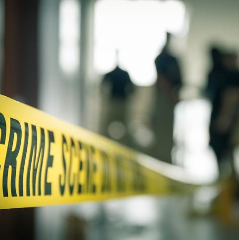 crime scene tape in building with blurred forensic team background